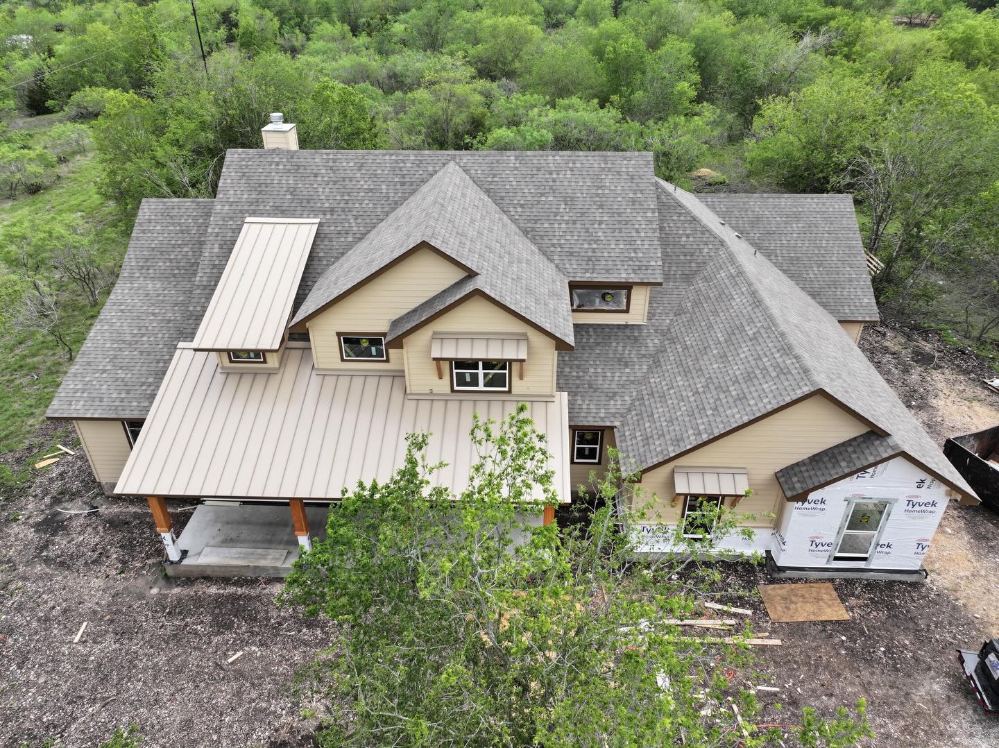 Aerial view of a custom home with shingle roofing and metal roof accents
